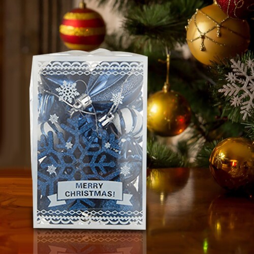 Closeup image of red gift box on wooden table in front of burning fireplace and Christmas tree