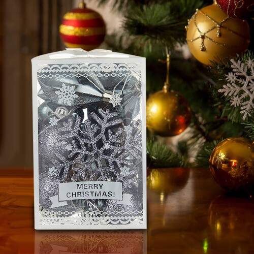 Closeup image of red gift box on wooden table in front of burning fireplace and Christmas tree